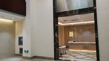 A hotel lobby with a reception desk, a seating area, and a marble floor.