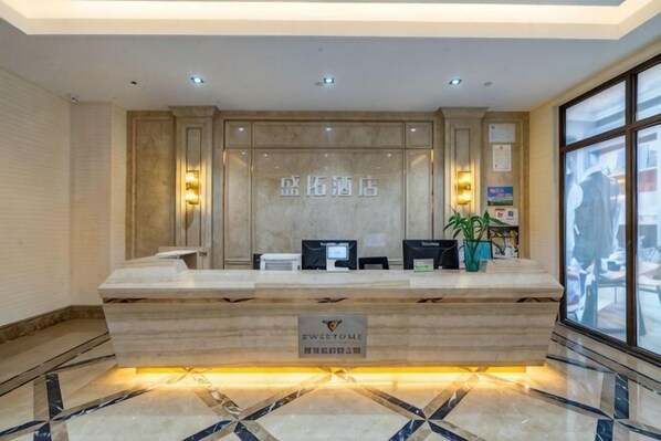 A reception desk with a marble counter, a digital screen, and a sign with Chinese characters.