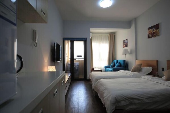 A hotel room with two beds, a desk, a chair, a TV, and a window with curtains. - Hangzhou Tonglu Shengtuo Serviced Apartment (Tonglu East Station Jiangnan Town) (Tonglu)