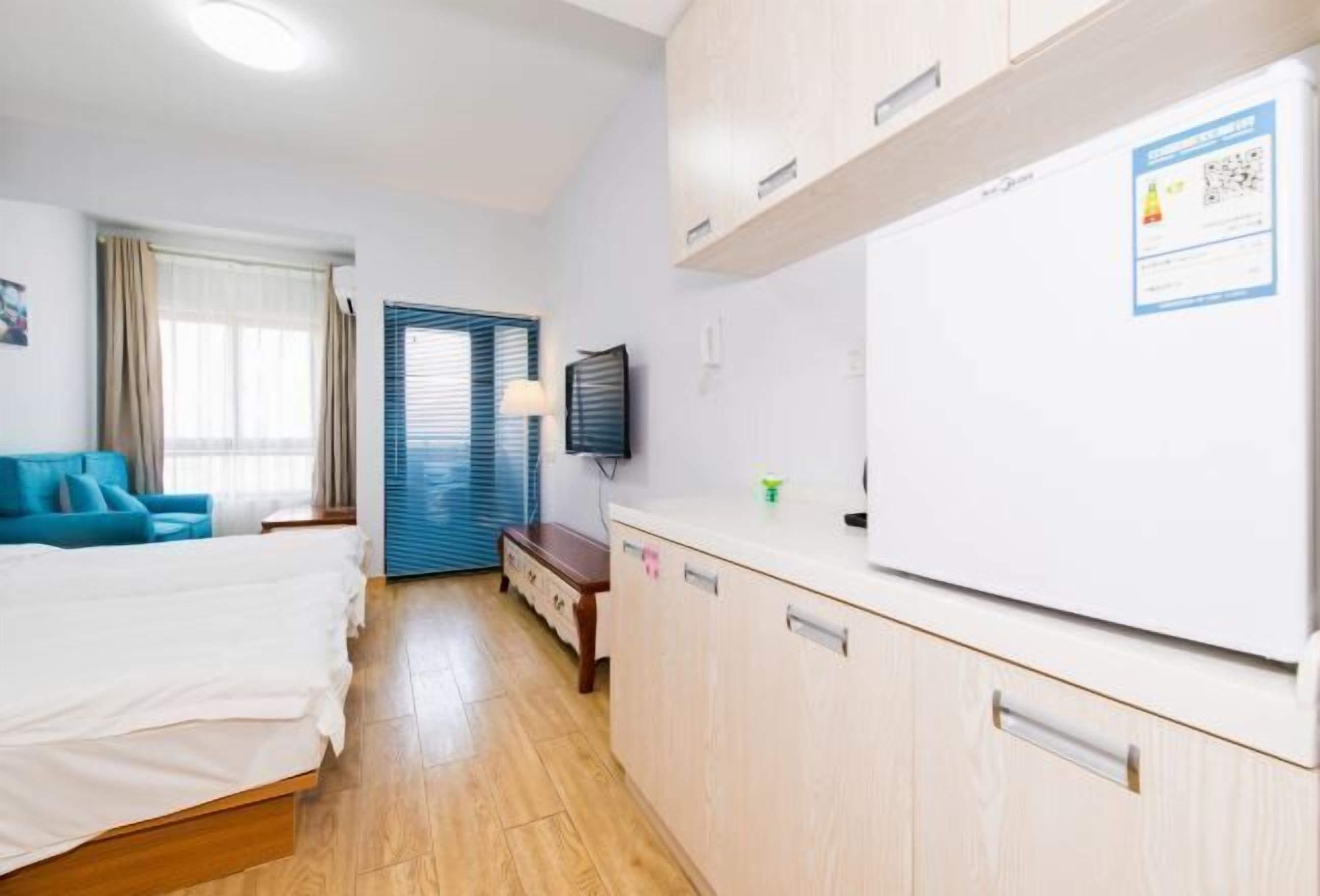 A hotel room with a bed, a desk, a chair, a TV, and a refrigerator.