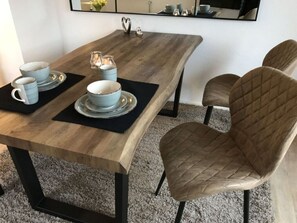 Ett matbord med en träskiva och svarta metallben, tillsammans med två stolar med stoppad klädsel i läder.