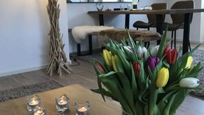 Ein Essbereich mit einem Holztisch, Kerzen und einer Tulpenvase.