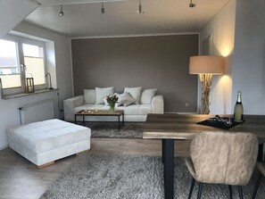Ett modernt vardagsrum med en soffa, ett soffbord och ett matbord med stolar.