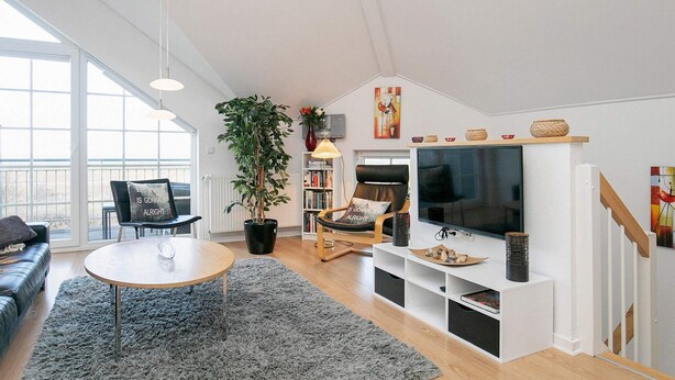 Ett modernt vardagsrum med en soffa, ett soffbord, en tv och en bokhylla.