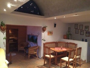 Un comedor con mesa y sillas de madera, una pequeña zona de cocina con mostrador, y un techo con diseño de estrellas.