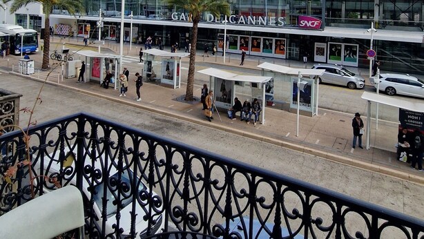 A balcony with a view of a city street, including a modern building with a sign reading "Gay Del Canneles". - HOTEL DU NORD (Cannes)