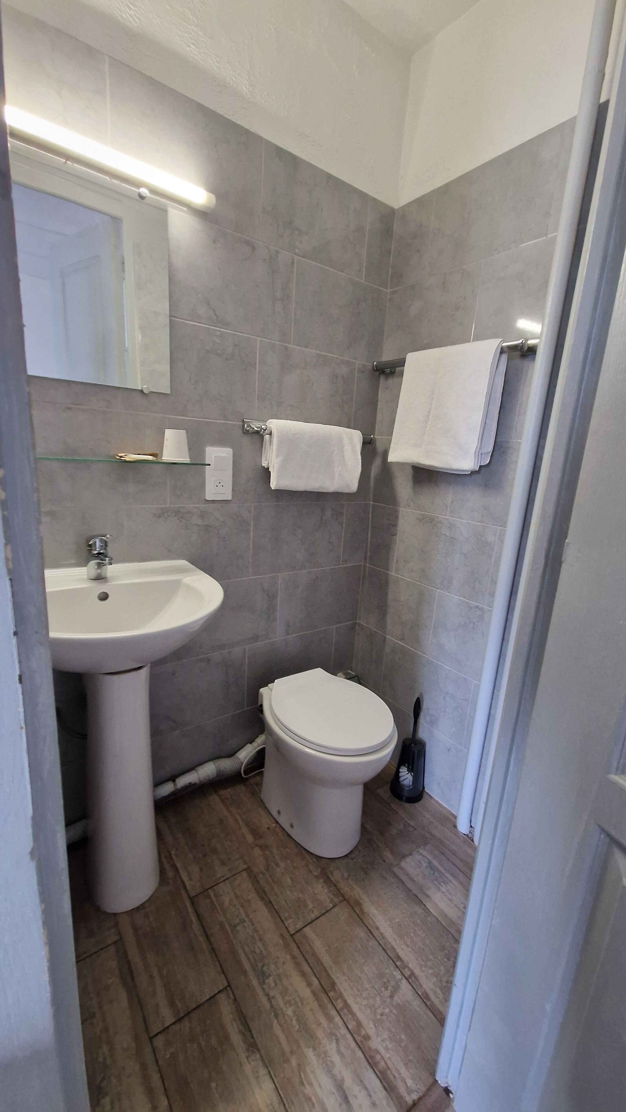 A bathroom with a sink, toilet, and a mirror.