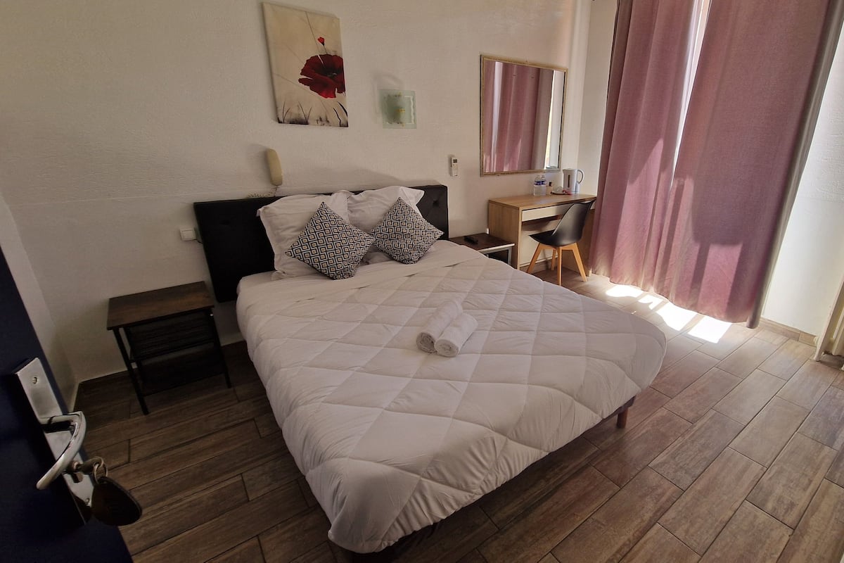 A neatly arranged bedroom with a bed, a desk, and a chair.