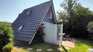 Una casa con tetto spiovente, una piccola finestra e un portone garage bianco.