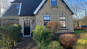 Ein zweistöckiges Haus mit dunklen Ziegeldach, einer Ziegelverkleidung und einer Haustür.