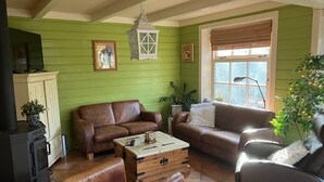 Ein gemütliches Wohnzimmer mit grünen Wänden, einem braunen Ledersofa, einem Couchtisch und einem Kamin.