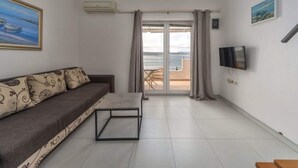 Ein Wohnzimmer mit einer Couch, einem Fernseher und einem Balkon mit Blick.