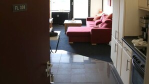 A compact living space with a kitchenette, a red sofa, and a dining area. - Ostseeliebe Comfortable Holiday Residence (Schönberg)