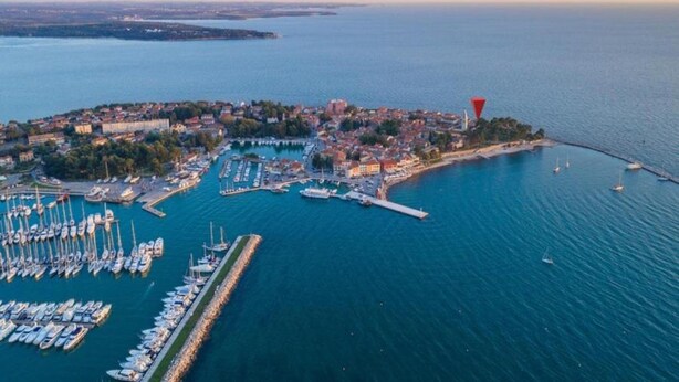 An aerial view of a coastal town with a marina, boats, and a lighthouse.