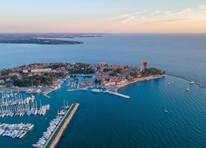 An aerial view of a coastal town with a marina, boats, and a lighthouse.