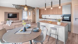 A modern kitchen with wooden cabinets, a central island, and pendant lighting.