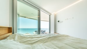 Un dormitorio con un amplio ventanal que da a un balcón con vistas al mar.