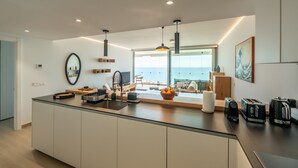 Una cocina moderna con una isla grande, vista al mar y diseño minimalista.