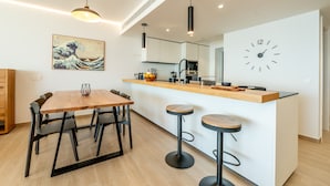 Una cocina moderna con una mesa de comedor de madera, taburetes de bar y un reloj grande en la pared.