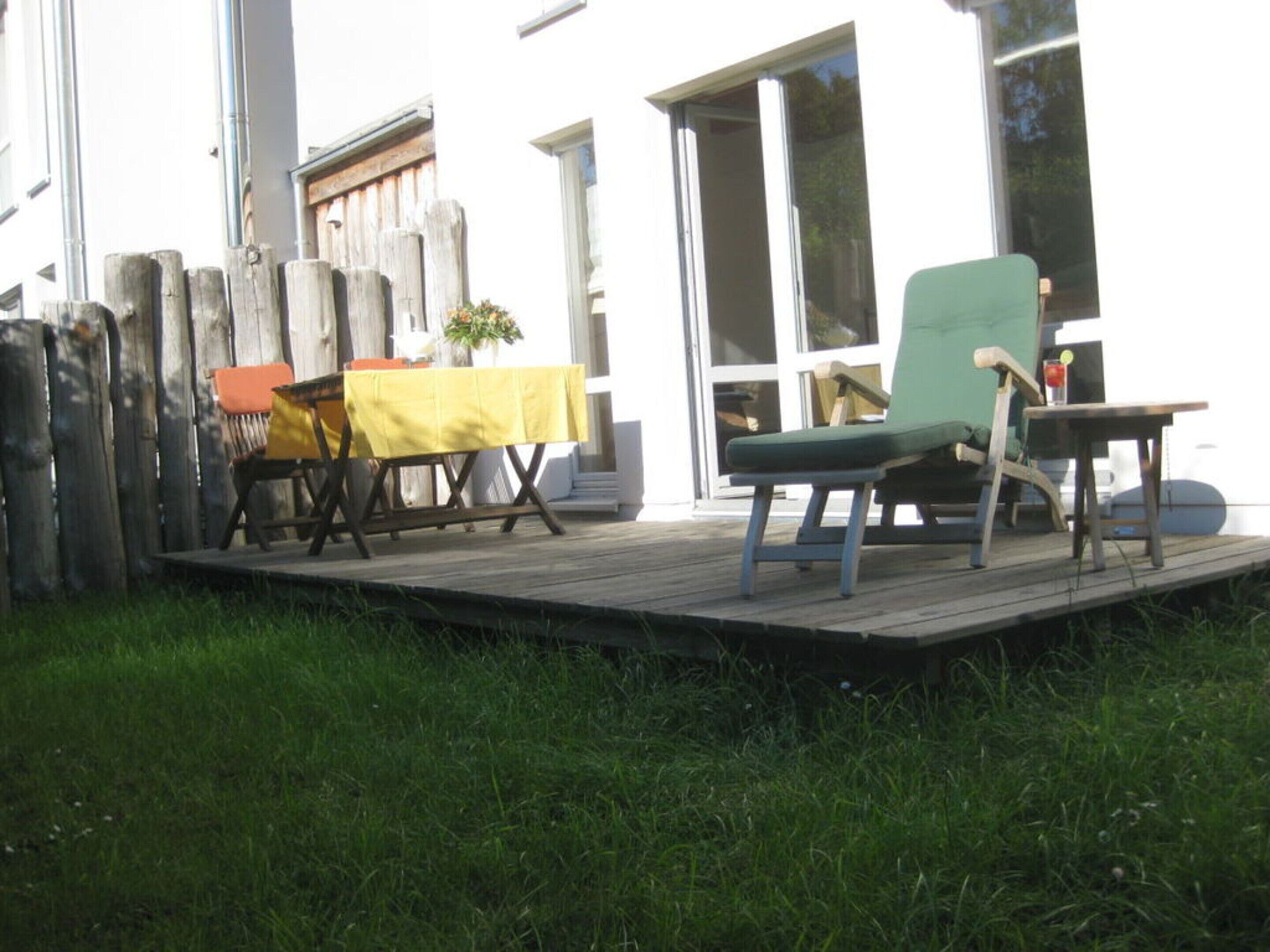 Une terrasse extérieure avec une table et des chaises, une clôture en bois et une maison en arrière-plan.