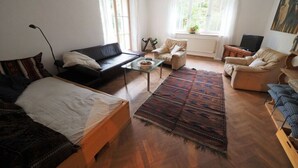 A spacious living room with a sofa, a chair, a coffee table, and a large rug. - Holiday Apartment Garden Paradise (Urbar)