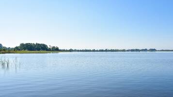 A calm lake with a distant tree line under a clear sky.