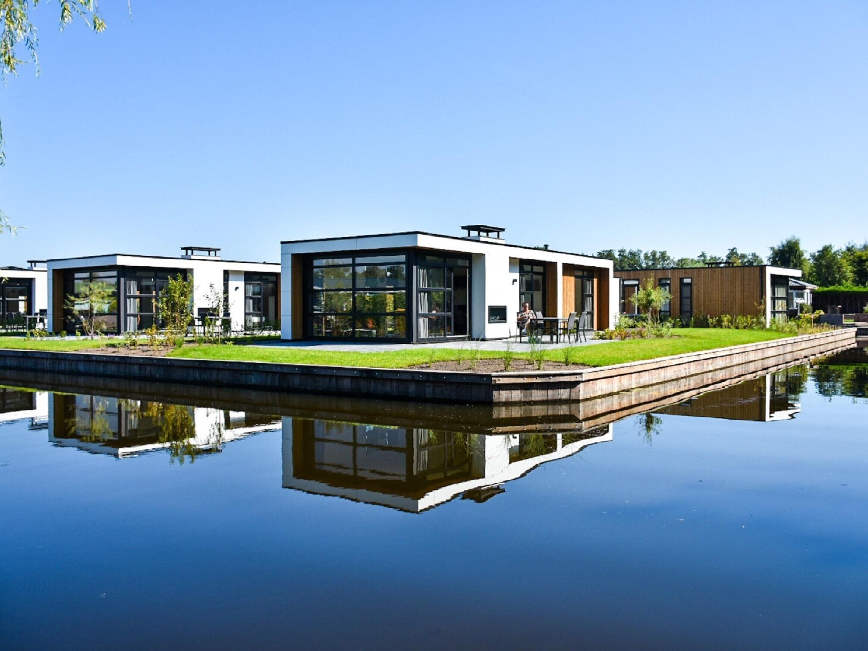 A modern building with large windows and a reflection in the water.