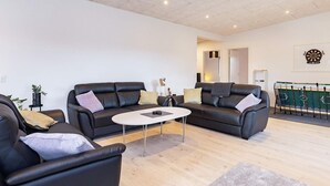 A modern living room with two black leather sofas, a white coffee table, and a foosball table. - 9 Person Holiday Home in Vaeggerlose (Vaeggerlose)