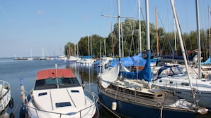 A marina with several boats docked, featuring masts and sails, and a calm water body in the background. - Waldhaus No.15 Modern Retreat (Monkebude)