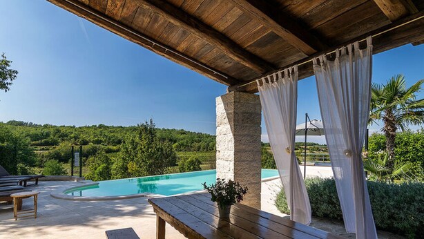 A wooden outdoor seating area with a pool and a view of a lush landscape. - Villa Zvonar Comfortable Holiday Residence (Karojba)