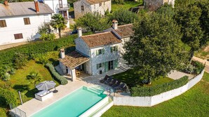 A large swimming pool with a white deck, surrounded by a well-maintained lawn and a stone wall. - Villa Zvonar Comfortable Holiday Residence (Karojba)