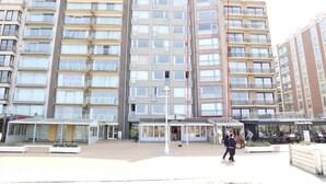 A multi-story residential building with balconies, a covered entrance, and a restaurant named "PRINCIPAL" in the foreground. - Chic Urban Seaside Apartment (Nieuwpoort)