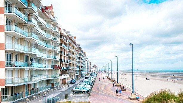 A beachfront hotel with multiple balconies, a parking lot, and a beach promenade. - Chic Urban Seaside Apartment (Nieuwpoort)