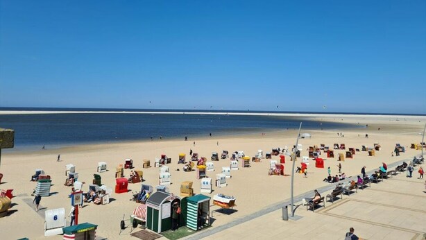 Een strand met veel strandhuisjes en een heldere blauwe lucht.