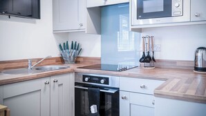 A modern kitchen with a built-in microwave, oven, and sink.