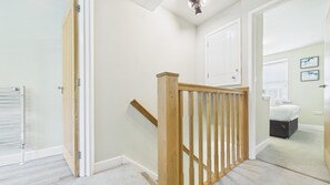 A hallway with a wooden staircase leading to a bedroom with a bed and a dresser. - Dolphin - 2 Bedroom Apartment - Saundersfoot (Saundersfoot)