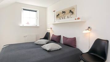 Une chambre à coucher comprenant un lit, deux lampes de chevet, une fenêtre et une œuvre d’art accrochée au mur.