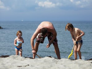 A beach scene with three people, two children and an adult, near the water. - 8 Person Holiday Park Home in Bogense (Bogense)