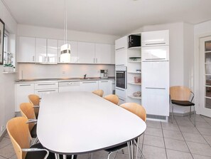 A modern kitchen with white cabinetry, a large island table, and a built-in oven. - 8 Person Holiday Park Home in Bogense (Bogense)