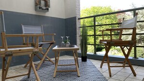 Een kamer met balkon, houten meubels, een kamerbreed tapijt met dessin en uitzicht op groen.