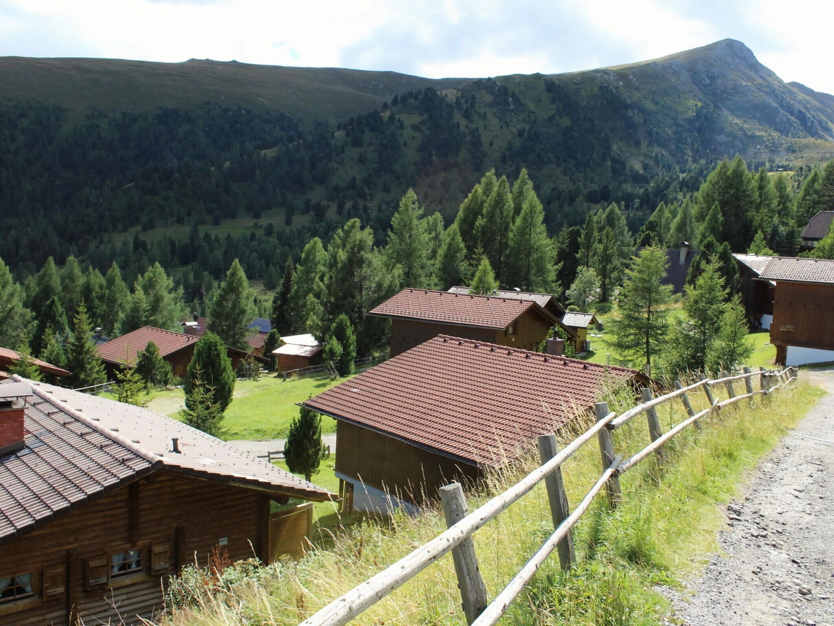 A rural mountain village with wooden houses and a dirt road.