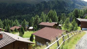 A rural mountain village with wooden houses and a dirt road.