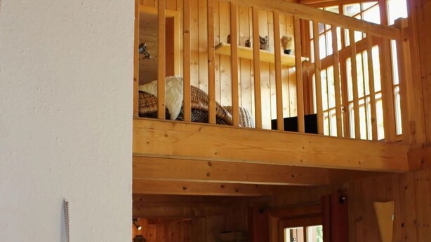 A wooden interior with a loft bedroom, a heart-shaped decoration, and a kitchen area. - Wiesbachhutte Mountain hut (Reichenau)