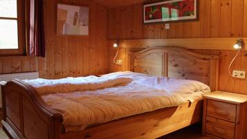 A wooden room with a bed, bedside table, and a painting on the wall.