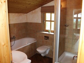 A bathroom with a bathtub, toilet, and shower area. - Wiesbachhutte Mountain hut (Reichenau)