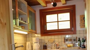 A compact kitchen with white cabinets, a tiled backsplash, and a window above the sink. - Wiesbachhutte Mountain hut (Reichenau)