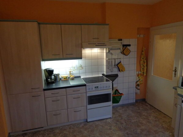 A compact kitchen with wooden cabinets, a stove, and a coffee maker. - Apartment on the Beach With sea View (Lohsa)