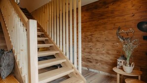 A wooden staircase with a sloped design, a small table with a basket, and a decorative item on the wall. - Chalet Salzach Near Ski Lift & Spa (Bramberg am Wildkogel)