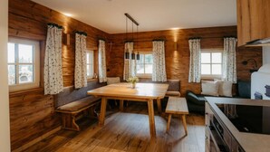 A cozy cabin-style room with wooden walls, a wooden dining table, benches, and a kitchenette. - Chalet Salzach Near Ski Lift & Spa (Bramberg am Wildkogel)
