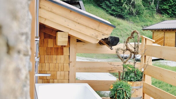 A wooden cabin with a wooden deck, a sink, and a heart-shaped wreath decoration. - Chalet Salzach Near Ski Lift & Spa (Bramberg am Wildkogel)